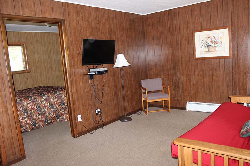 Motel Suite 9 living room with futon sofa, chair, and wall-mounted TV